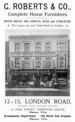A black-and-white advert showing an illustration of a three-storey double shopfront. The bottom of the image looks photorealistic, but the upper floors appear more like a drawing. Text above the image reads: “G. Roberts & Co., Complete House Furnishers. Noted house for carpets, rugs and linoleums. The Largest and most Varied Stock in Croydon.”. Text below the image reads: “13-15 London Road, opposite West Croydon Station. 43, High Street, Thornton Heath. ’Phone 774. Gramophone Department - 143, North End, Croydon. ’Phone 773.”