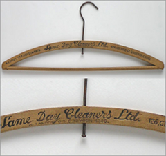 Two pictures of the same wooden coat hanger, which has “Same Day Cleaners Ltd” stamped into the middle of it.  One of the pictures shows the full item and the other is a close-up on the name of the business.  Two addresses are also stamped into the coat hanger on either side of this.