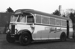A black-and-white photo of a coach with windows all along the side and a sliding door at the back. The blind at the front reads “CROYDON”. “John Bennett” is printed on the side of the coach in a cursive font.