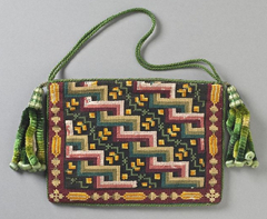 A rectangular purse decorated with counted-thread embroidery in red, yellow, orange, green, and light brown. A tasselled cord in shades of green is attached to the top at both sides.