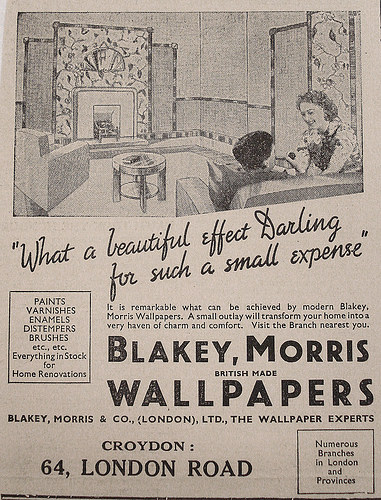 A newspaper advertisement for “Blakey, Morris British Made Wallpapers” at 64 London Road, Croydon.  A line drawing at the top shows two people talking in a living room with striking patterned wallpaper, with cursive letters underneath reading “What a beautiful effect Darling for such a small expense”.