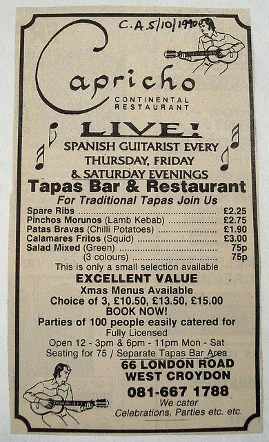A newspaper advertisement headed: “Capricho Continental Restaurant / Live! Spanish guitarist every Thursday, Friday & Saturday evenings / Tapas Bar & Restaurant”.  Some sample menu prices are given, including spare ribs at £2.25, patas bravas (chilli potatoes) at £1.90, and calamares fritos (squid) at £3. Line drawings of the Spanish guitarist are included in the top-right and bottom-left corners.  Someone has written “C.A. 5/10/1990” in ink at the top of the clipping.
