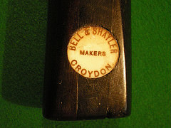 The end of a billiards cue with a circular imprint reading “Bell & Shayler / Makers / Croydon”.