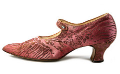 A salmon-pink brocade shoe with a medium-high heel and a slightly pointed tow.