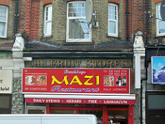 An old sign reading “The Fruit Stores”, visible above a newer sign reading “Mazi”.