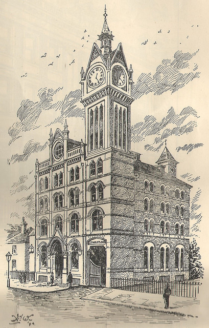 A monochrome drawing of a four-storey building with a clocktower reaching further up from one corner.  A weathervane can just be seen on another tower in the opposite corner, behind.  Two or three steps lead up to a grand arched entrance on the left, and on the right below the clocktower is a wide goods entrance with the words “J Thrift & Sons” above.
