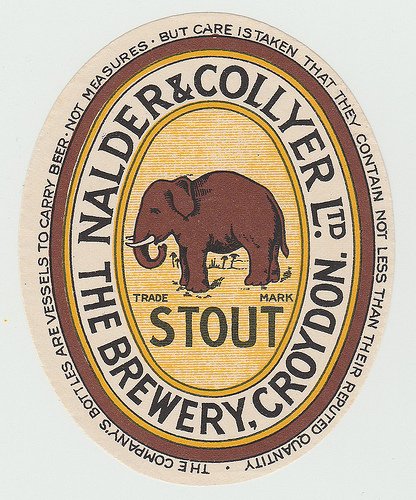 An oval label with a dark brownish-red elephant in the
centre, the words “Trade Mark” and “Stout” beneath, and “Nalder &
Collyer Ltd / The Brewery, Croydon” winding around it.  At the very
edge of the label are more winding words: “The company’s bottles are
vessels to carry beer - not measures - but care is taken that they
contain not less than their reputed quantity.”