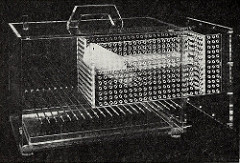 A black-and-white photo of a clear plastic box with a pull-out section studded with airholes.  Some sort of tube, possibly a drinking bottle, is inside, but the details are unclear.