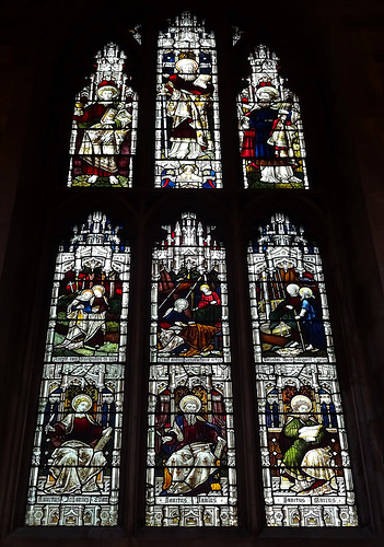 A stained-glass window with nine panels showing various saints.