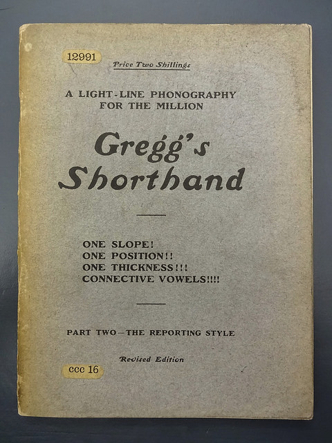 The cover of a small, thin pamphlet.  It appears to have once been blue, but now has yellowing around the edges, and reads: “Price Two Shillings / A Light-Line Phonography for the Million / Gregg’s Shorthand / One Slope!  One Position!! One Thickness!!! Connective Vowels!!!! / Part Two — The Reporting Style / Revised Edition”.