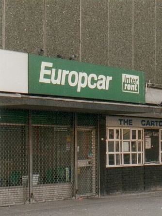 A small shopfront with a green and white “Europcar / inter rent” sign above.  The shopfront itself is covered with a metal mesh shutter.  It’s unclear whether the shop has closed down or is merely not open at the time of photography.