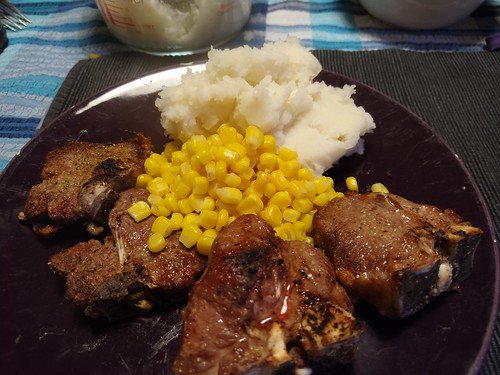 A large purple plate containing a mound of mashed potato, a heap of sweetcorn, and four of the lamb chops, now cooked to brownness.