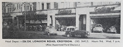 A low-resolution newspaper photo of an extensive shop frontage spanning five individual shop premises and three recessed entrances to the flats above.  The fronts of the shops have been opened up to display cars and motorbikes inside.  Signs above read “Godfreys”.  Text underneath the photo reads: “Head Depot:— 226/234, London Road, Croydon.  CRO. 3641/3.  Hours 9–6.  Wed. 1 p.m.  (Also Appointed Ford Dealers.)