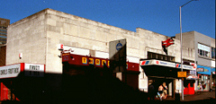 A breezeblock building with a Threshers off licence in its left-hand part and a railway station entrance in its right-hand part. The photo was taken in late-afternoon sunlight with heavy shadows.