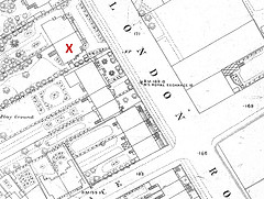 A black-and-white map showing building footprints, gardens, and two intersecting roads.