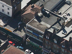 Aerial photo of shops showing a variety of architectural styles including mid-1800s houses completely surrounded by later extensions.