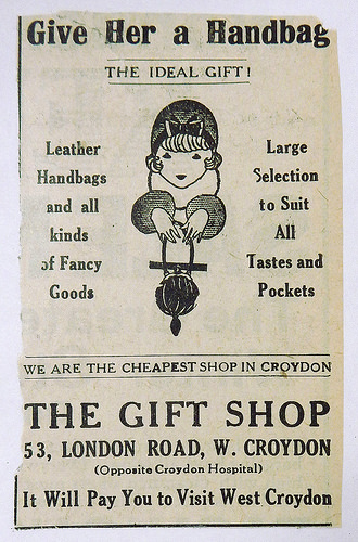 A black-and-white newspaper advert with a drawing of a women holding a fancy handbag and the text: “Give Her a Handbag / The Ideal Gift! / Leather Handbags and all kinds of Fancy Goods / Large Selection to Suit All Tastes and Pockets / We are the cheapest shop in Croydon / The Gift Shop / 53, London Road, W. Croydon / (Opposite Croydon Hospital) / It Will Pay You to Visit West Croydon”