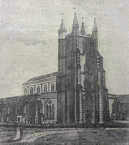 A church building with a large square tower at one end.  Two people, one in a white dress and one in a dark suit, are standing on the path that leads up to the entrance.