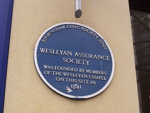 A round dark blue plaque mounted on a light cream wall, reading: “Birmingham Civic Society 2001 / Wesleyan Assurance Society was founded by members of the Wesleyan Chapel on this site in 1841”.