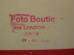 Close-up on a beige and red envelope with the words “Foto Boutique / 206 London [unreadable] / Croydon” stamped on it in red ink.