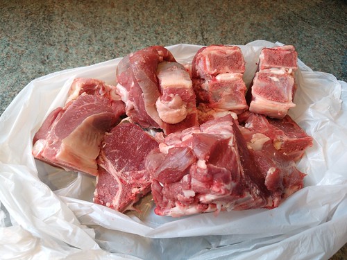 Several raw lamb chops inside a white plastic carrier bag.