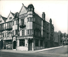 A wider view of the corner premises above, showing all three floors of the building as well as its neighbours on both main road and side road.  The sign now reads “Westminster Bank”.  The floors above have arch details in the brickwork, small-paned windows, and a dome at the very top on the corner.