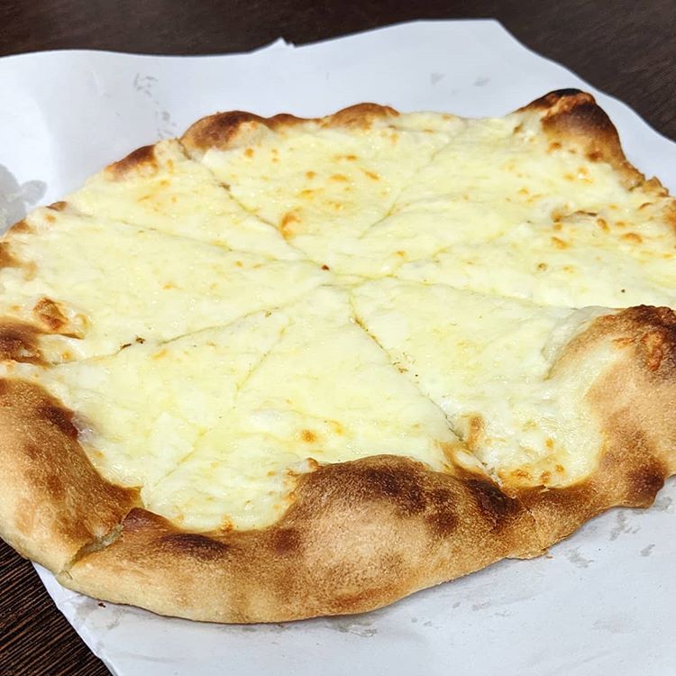 An oval flatbread topped with melted cheese, sliced into eight portions.  The edges of the bread are browned and puffed up.