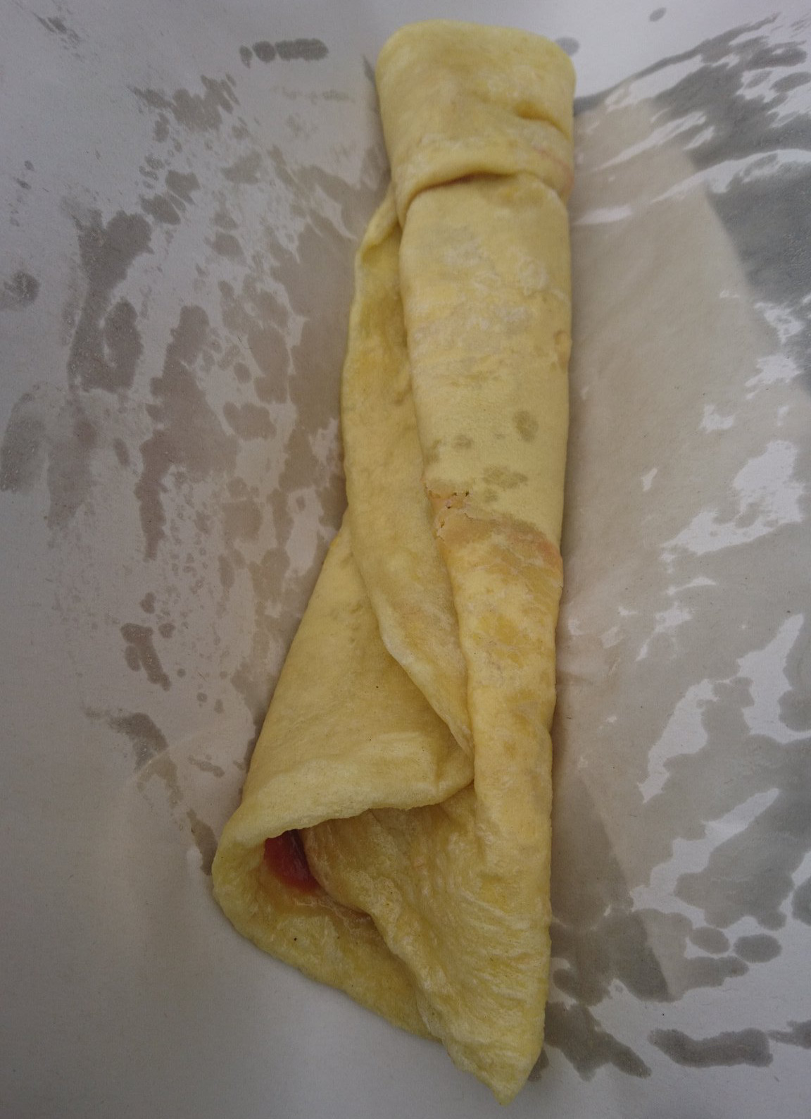 A soft, flexible flatbread rolled up and placed in a paper wrapping.